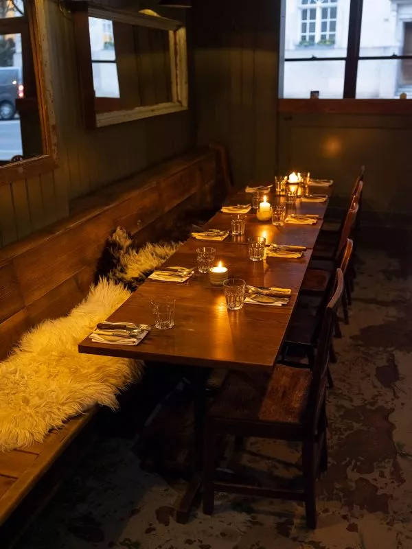 Candle lit table laid for 10 guests with long bench and chairs